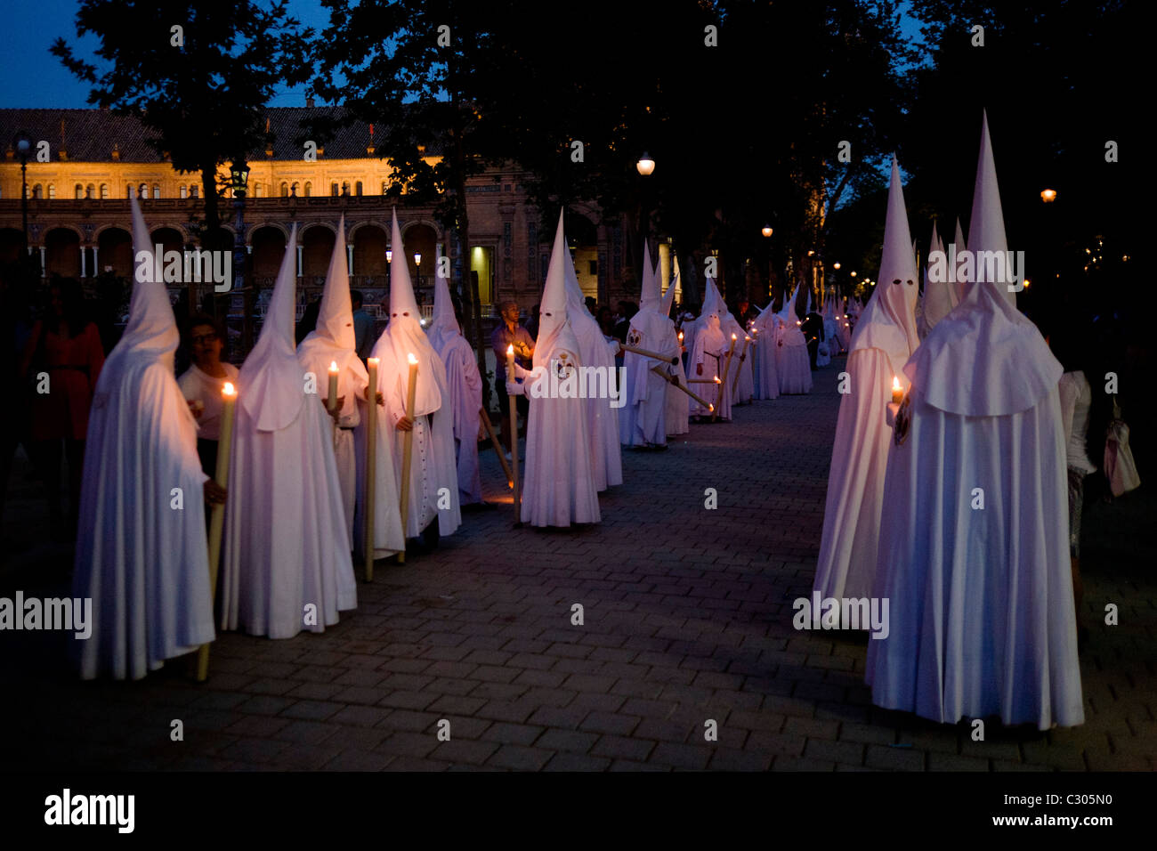 Hooded penitents (Nazarenos) in candlelit procession during Seville's annual Easter Holy Week (Semana Santa de Sevilla) Stock Photo