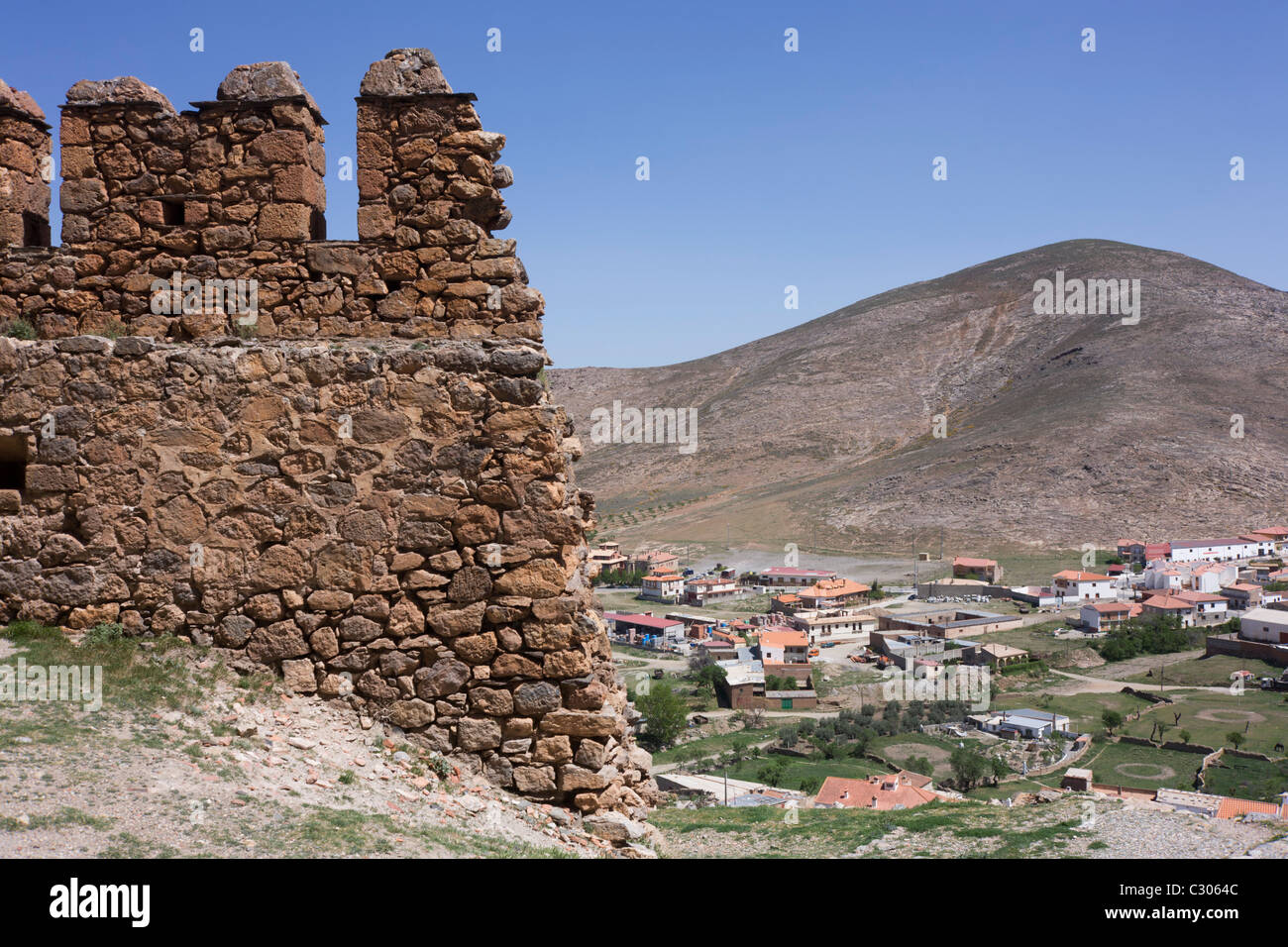 Stones and wall fortifications of the medieval La Calahorra Castle and modern town below. Stock Photo