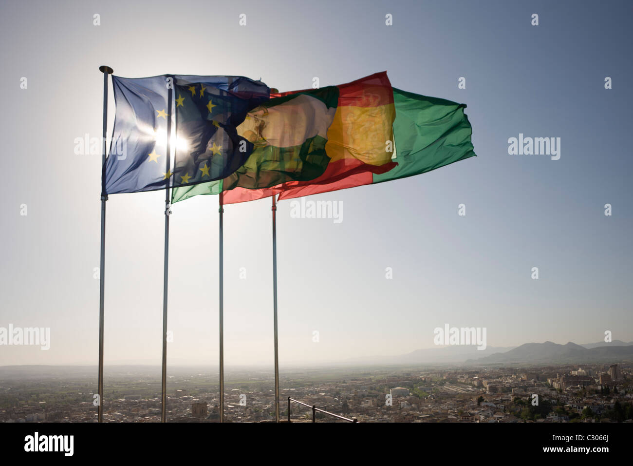 The Spanish, Andalucian and EU flags flying high over city of Granada on top of Alhambra's Torre de la Vela (Watchtower) Stock Photo