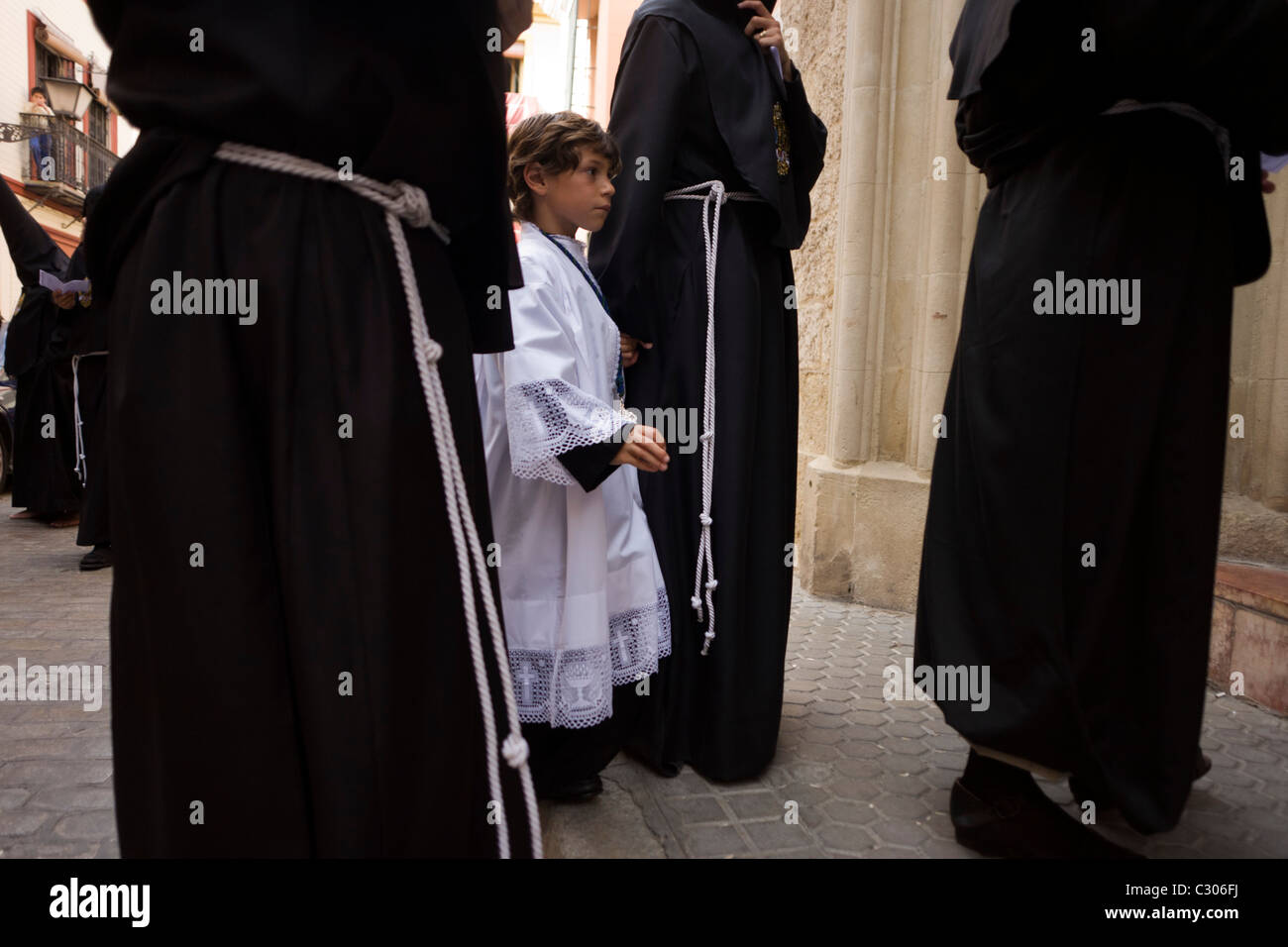 Altar boy and hooded penitents (Nazarenos) gather for Seville's annual Semana Santa Easter passion processions. Stock Photo