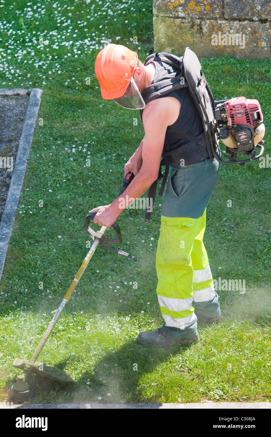Council worker strimming grass border - France. Stock Photo