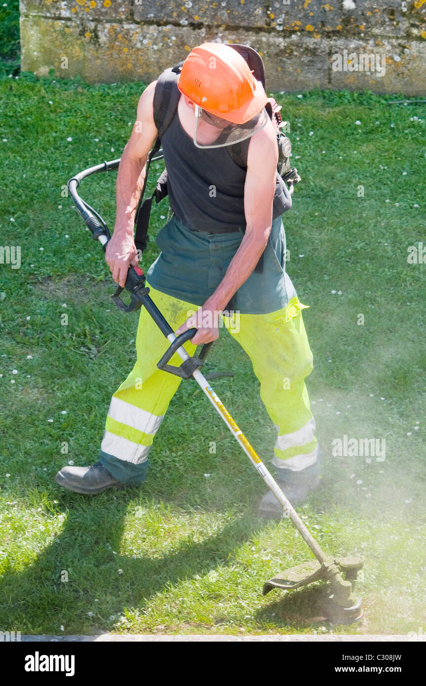 Council worker strimming grass border - France. Stock Photo