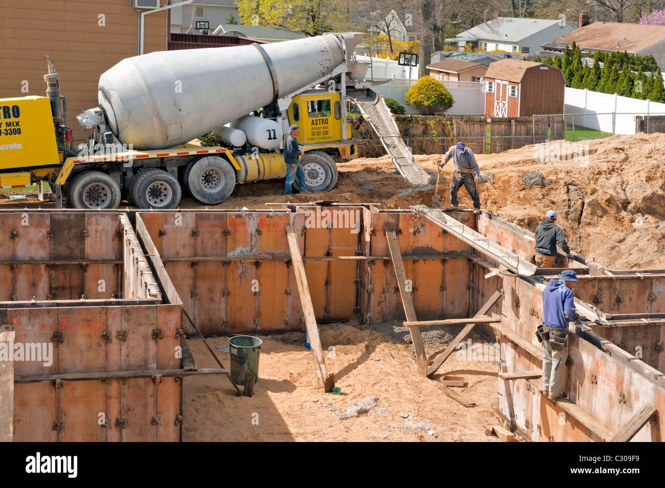 New home construction workers setting up cement mixer chute to pour