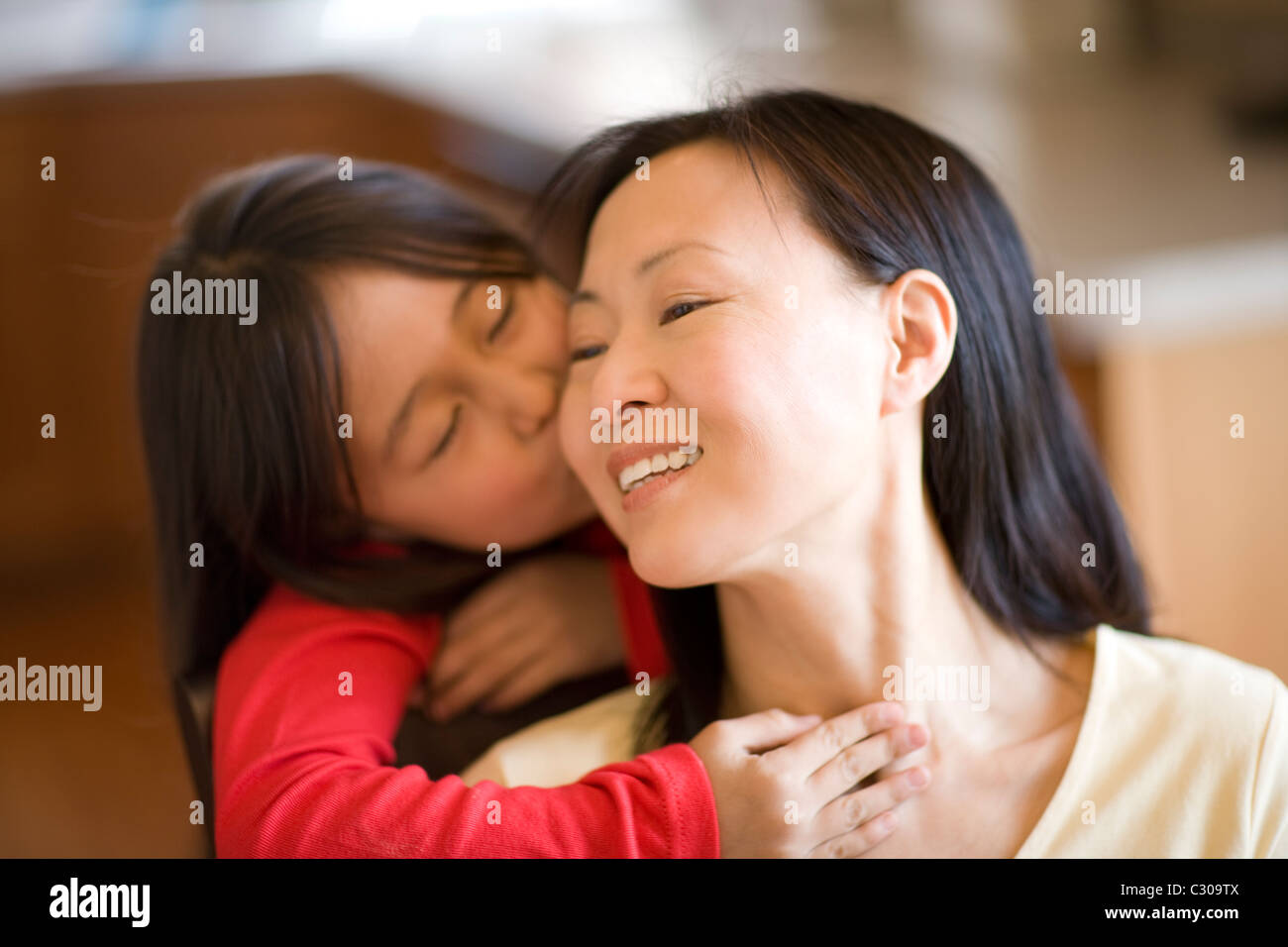 Asian daughter hugging and kissing mother Stock Photo
