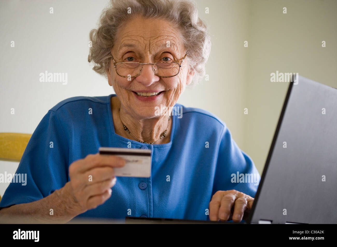 Smiling senior woman using credit card and laptop Stock Photo