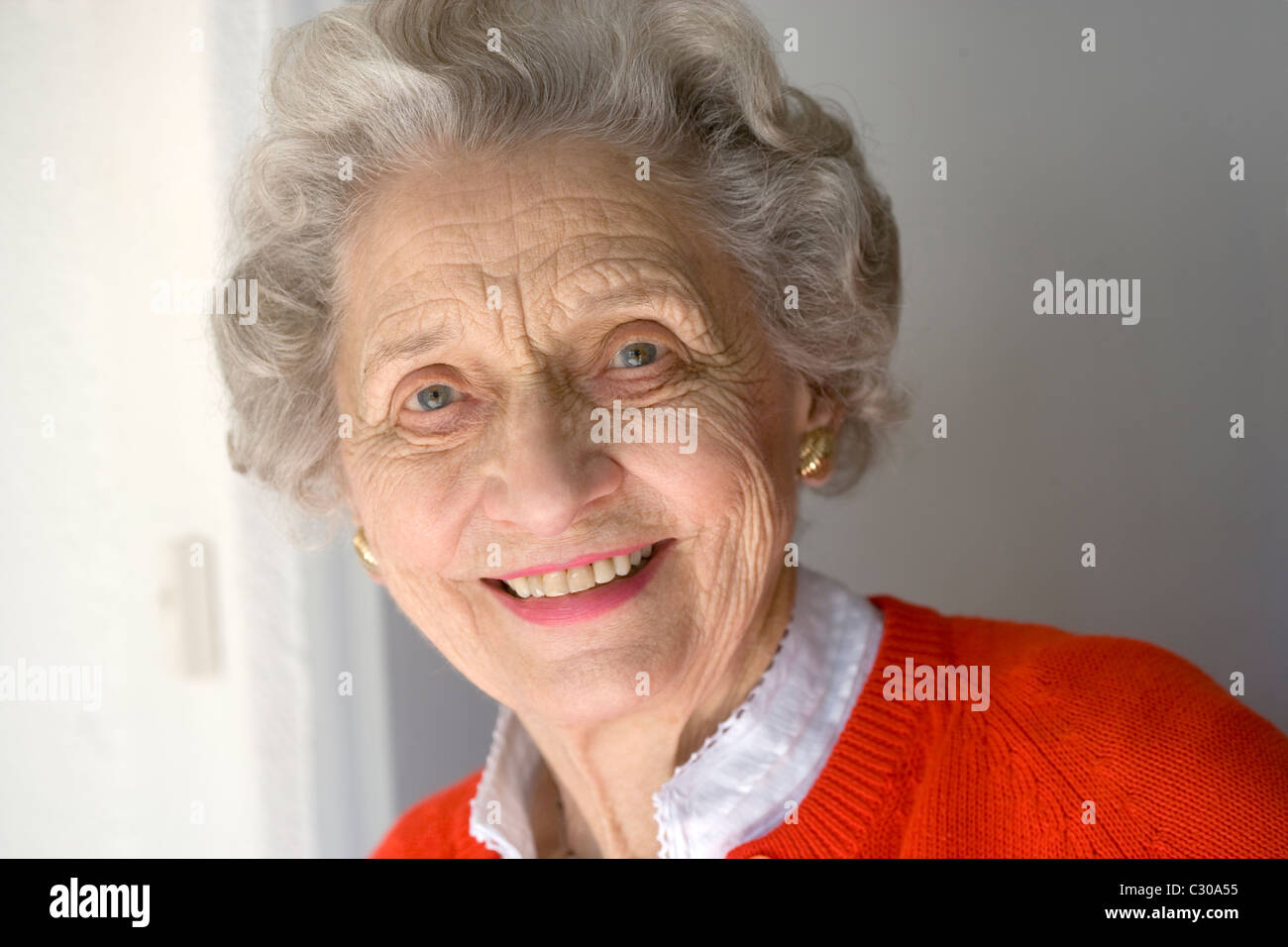 Portrait of attractive senior woman standing by front door Stock Photo
