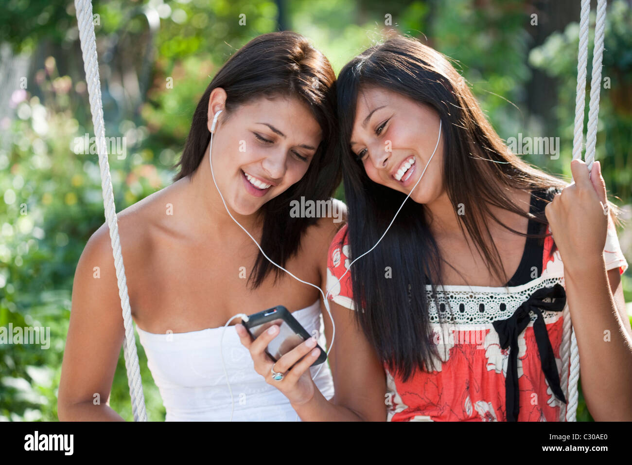 Two teenage girls sharing an MP3 player and smiling Stock Photo