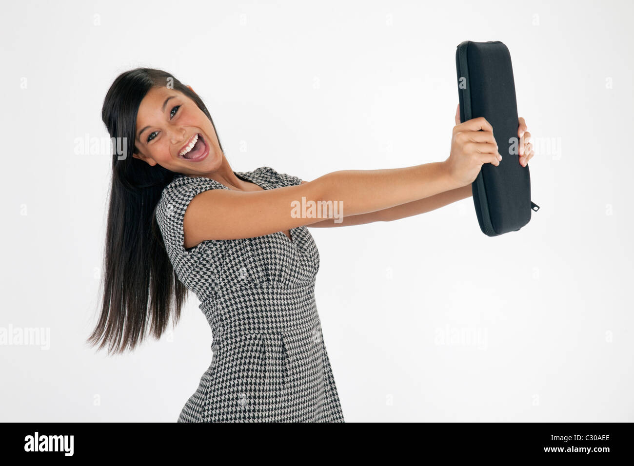 Pretty young Asian woman laughs while holding out a laptop case against a white background. Horizontal shot. Stock Photo