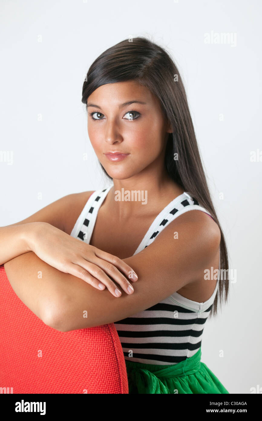 Attractive young Asian woman poses with her arms crossed atop a chair back. Vertical shot. Stock Photo