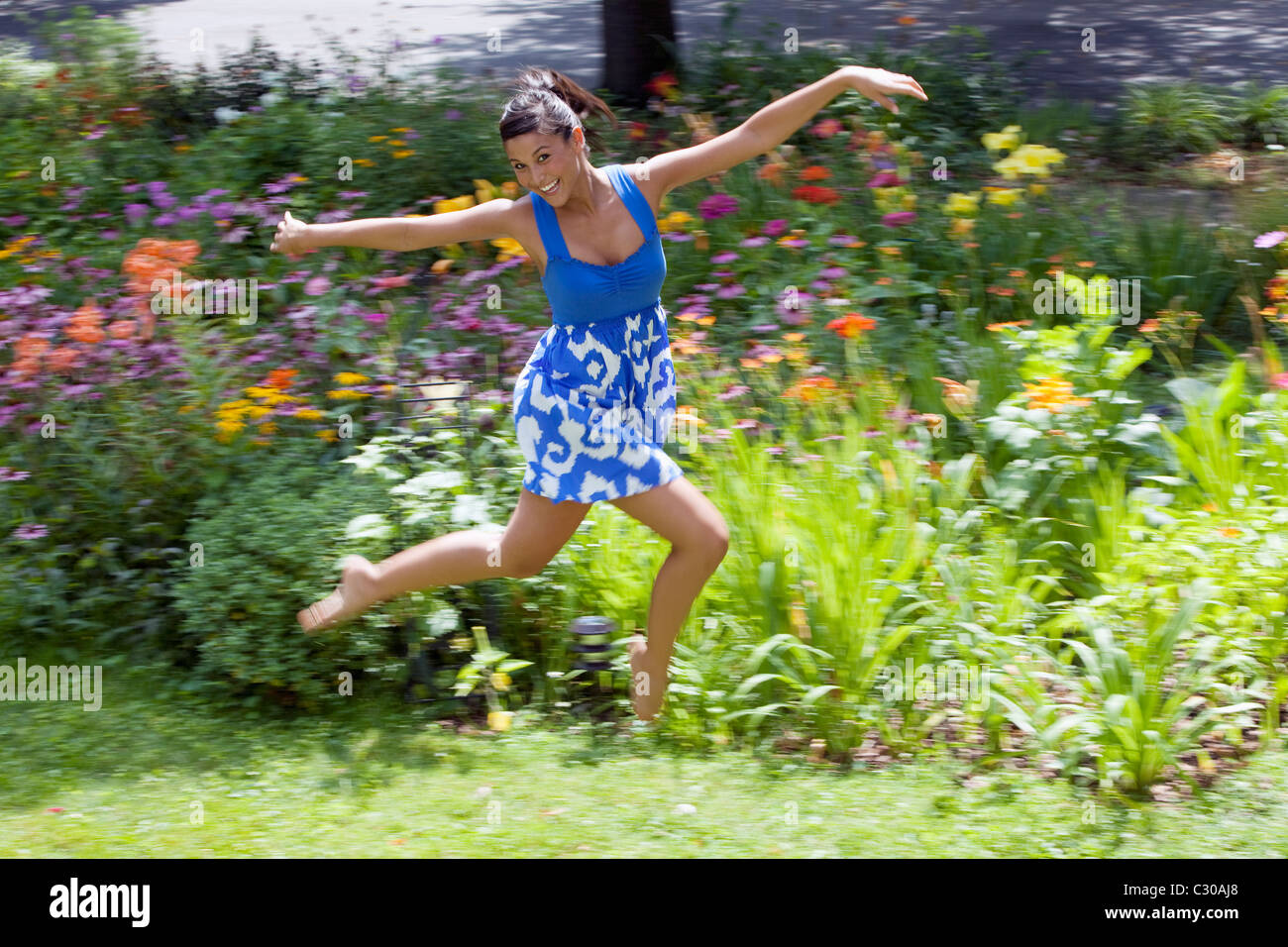 young Asian woman leaping for joy in the garden Stock Photo