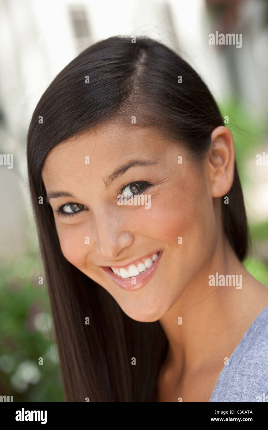 Portrait of a beautiful Asian woman smiling into the camera in an outdoor setting. Vertical shot. Stock Photo