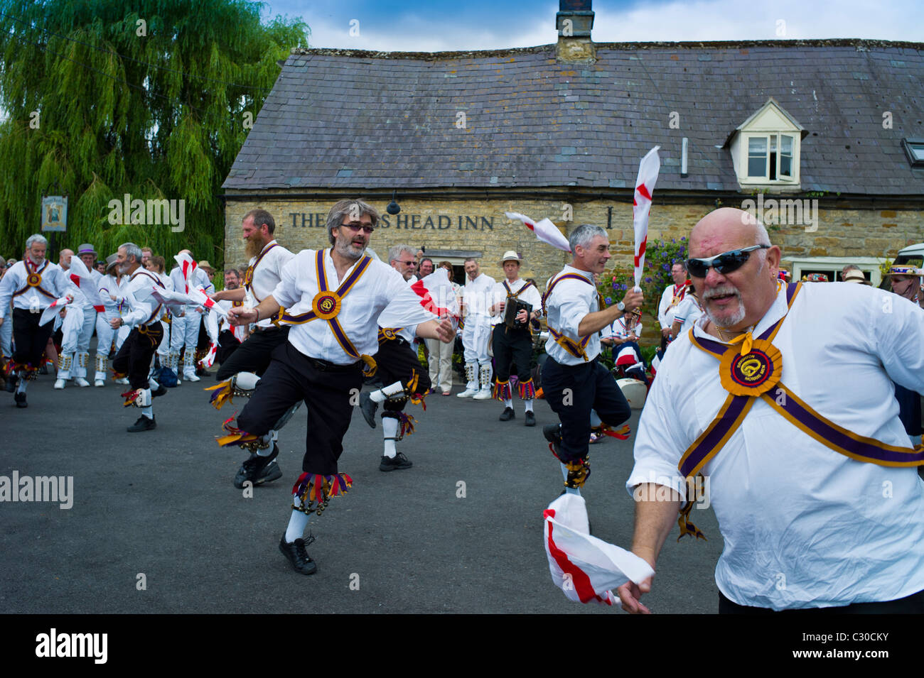 Morris dancers, Brighton Morris Men, perform a dancing display at The Kings Head Pub in Bledington, Oxfordshire, UK Stock Photo