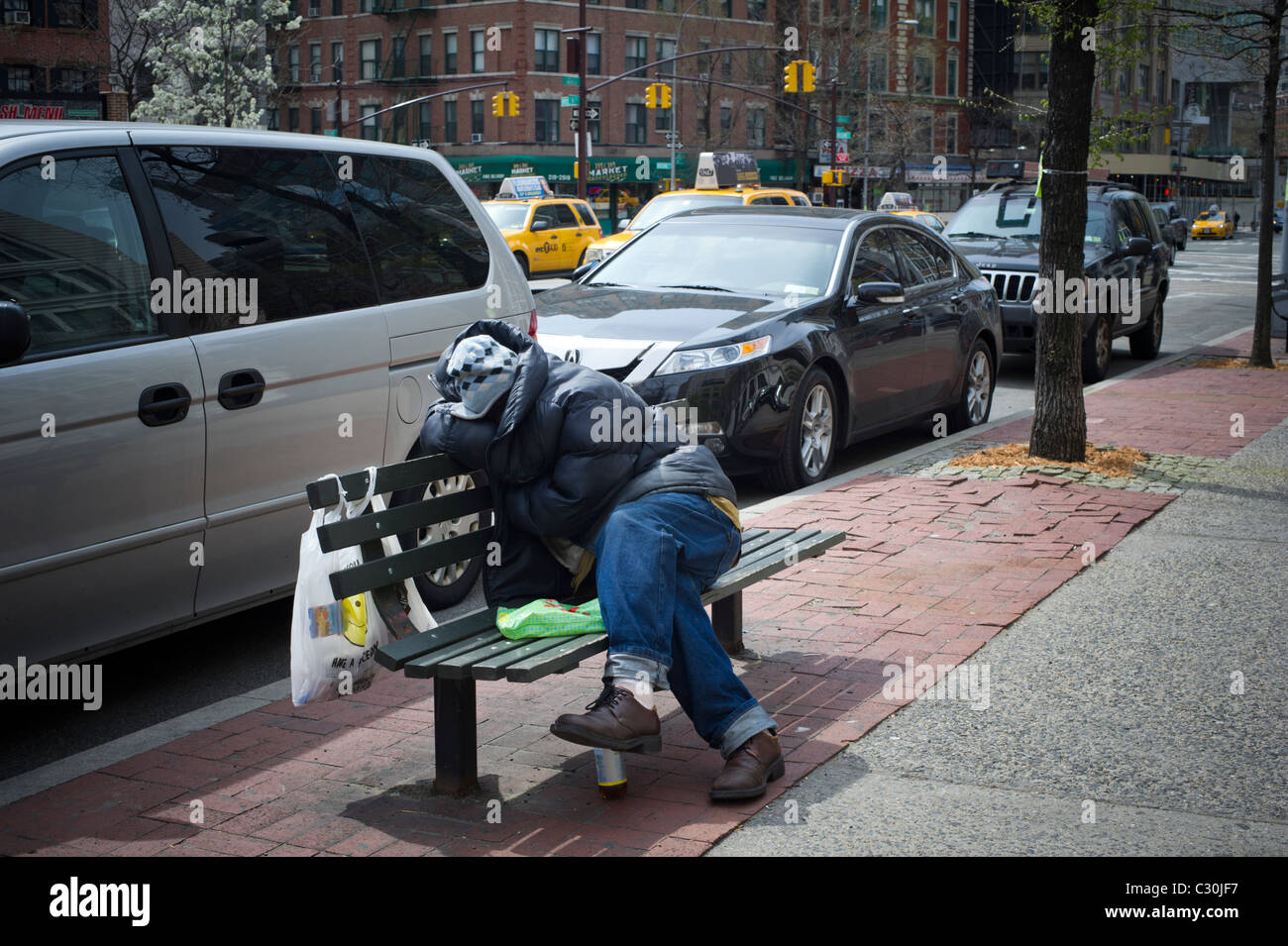 A homeless man sleeping on a park bench in lower Manhattan in New York ...