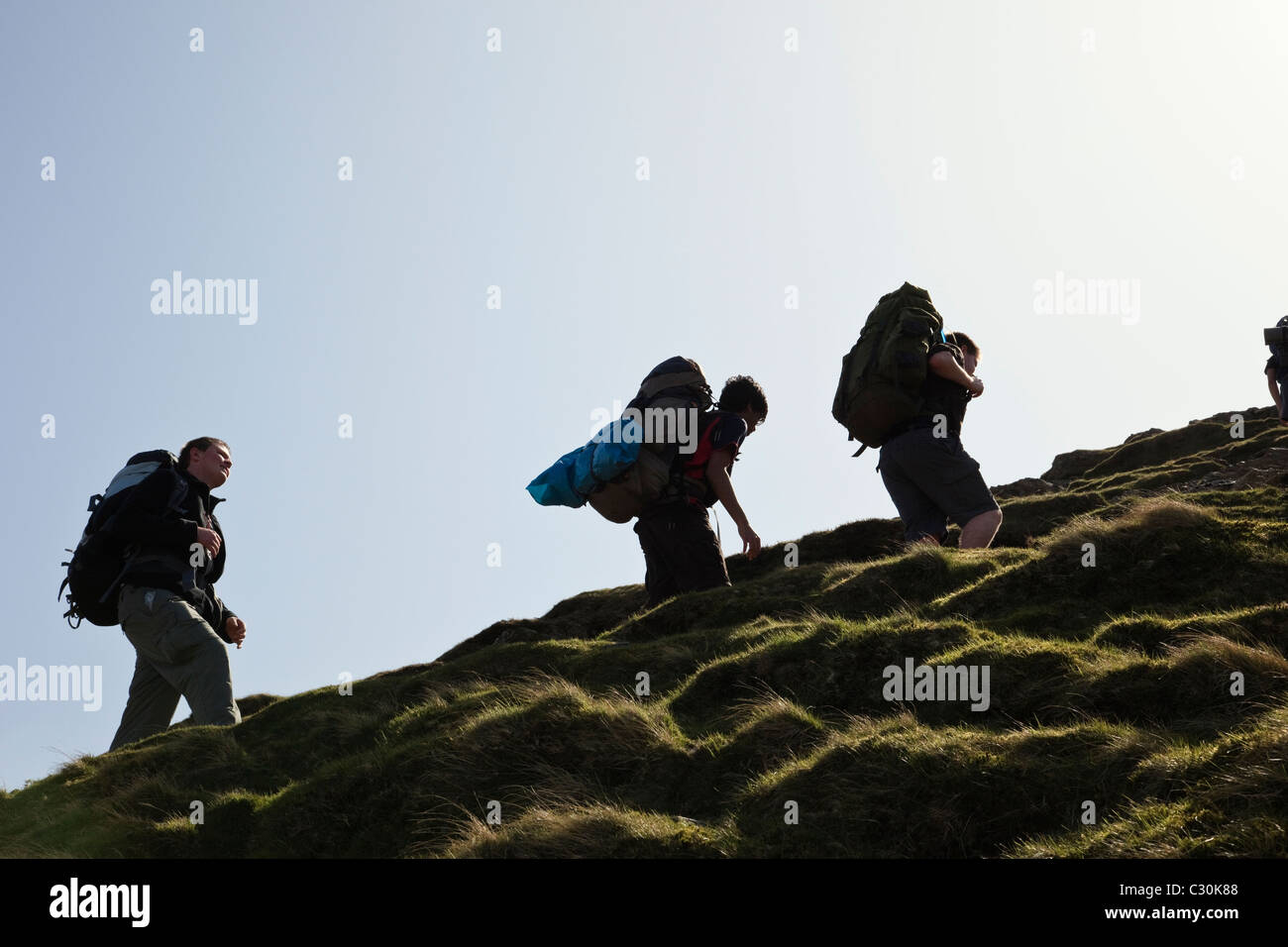 Young people backpacking on Duke of Edinburgh Award scheme expedition climbing up Cat Bells in Lake District National Park Cumbria England UK Britain Stock Photo