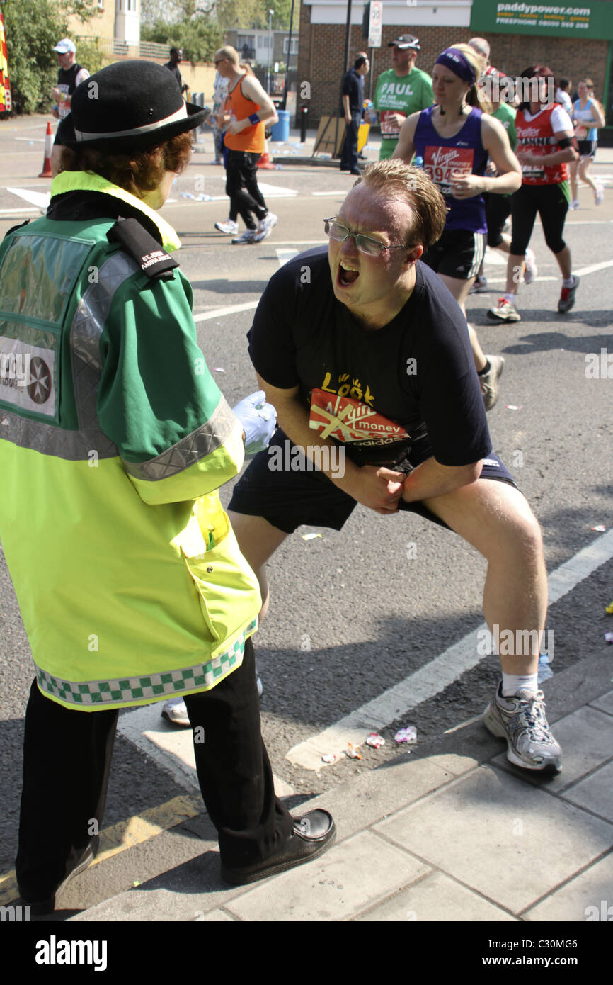 Runner accepts petroleum jelly from St. John's Ambulance volunteer to relieve painful chafing on route of London Marathon Stock Photo