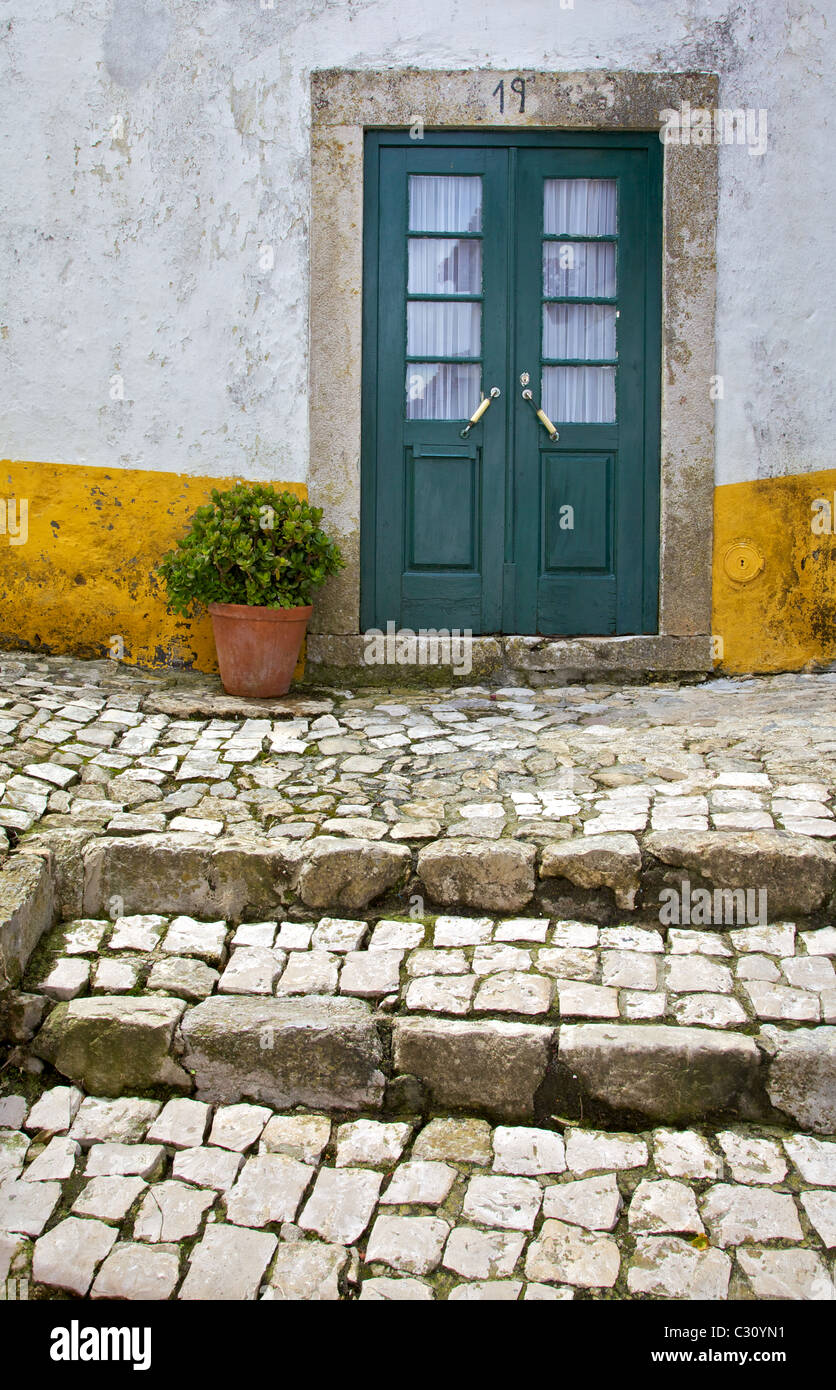 Green Weathered Wood Door Against a White & Yellow Plaster Wall of the Medieval Village of Obidos Stock Photo