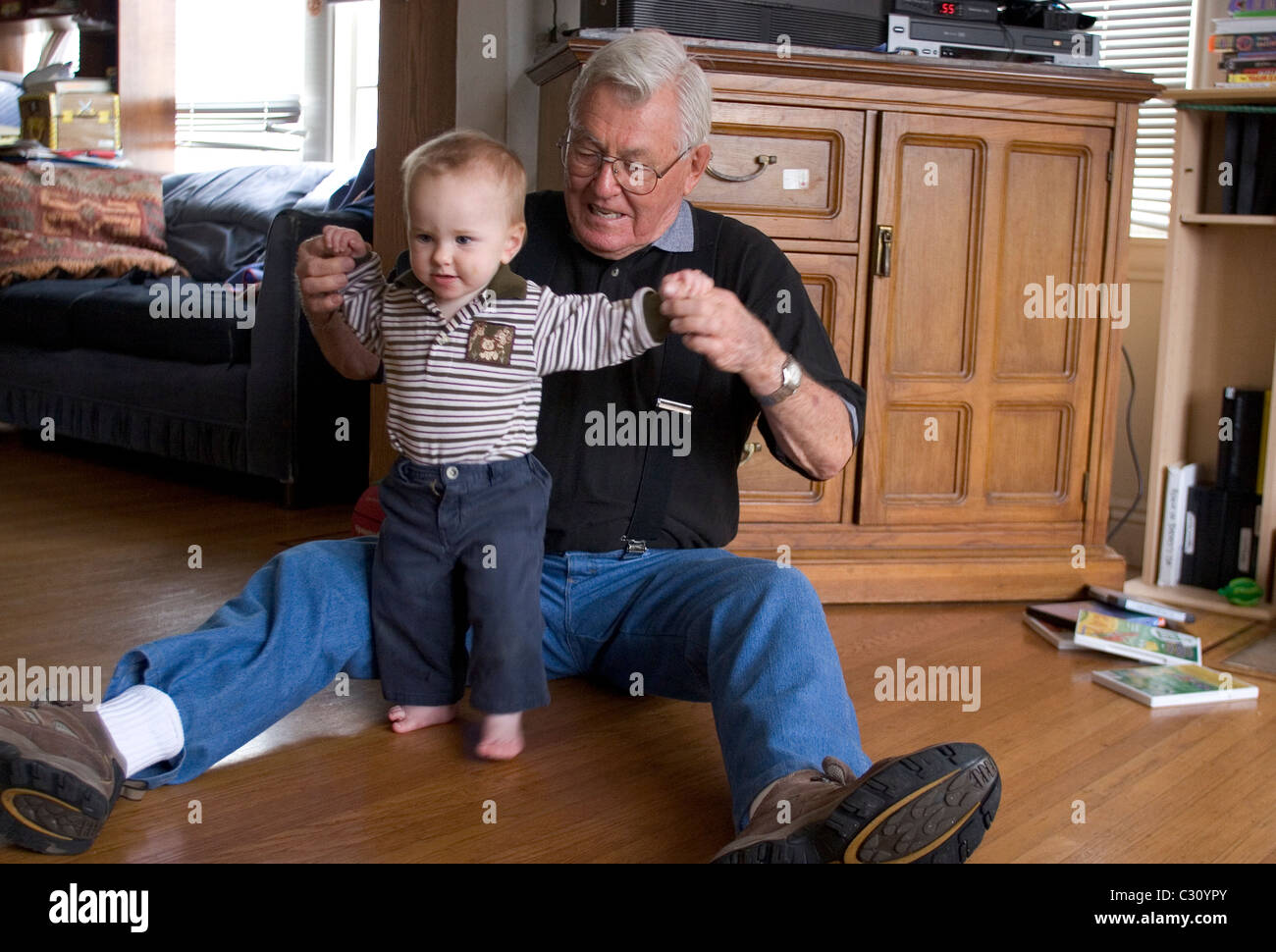 15 month old baby boy taking his first steps as his grandfather watches. Stock Photo