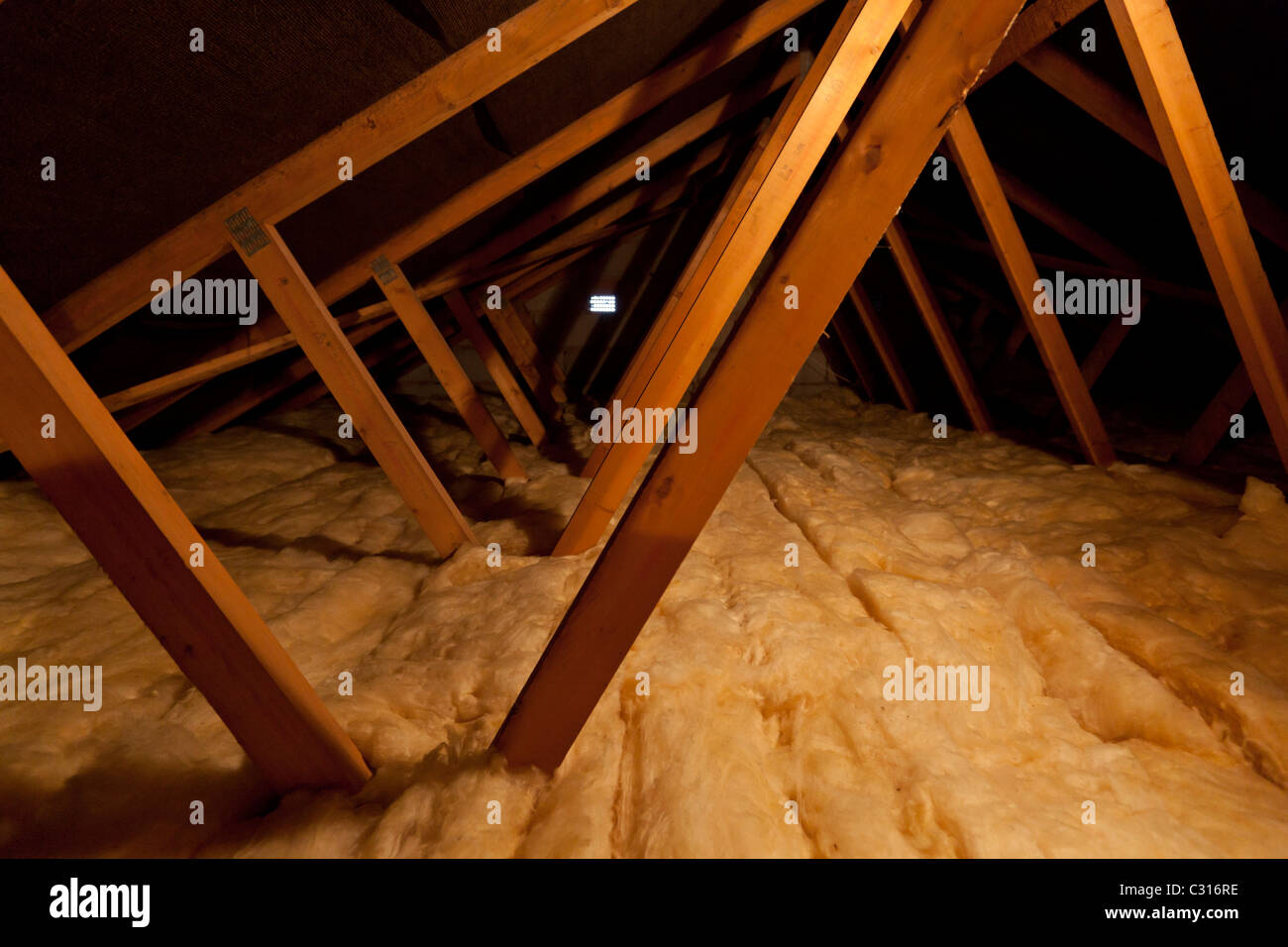Inside a house loft putting extra insulation to increase warmth and thermal efficiency by adding additional loft insulation Stock Photo
