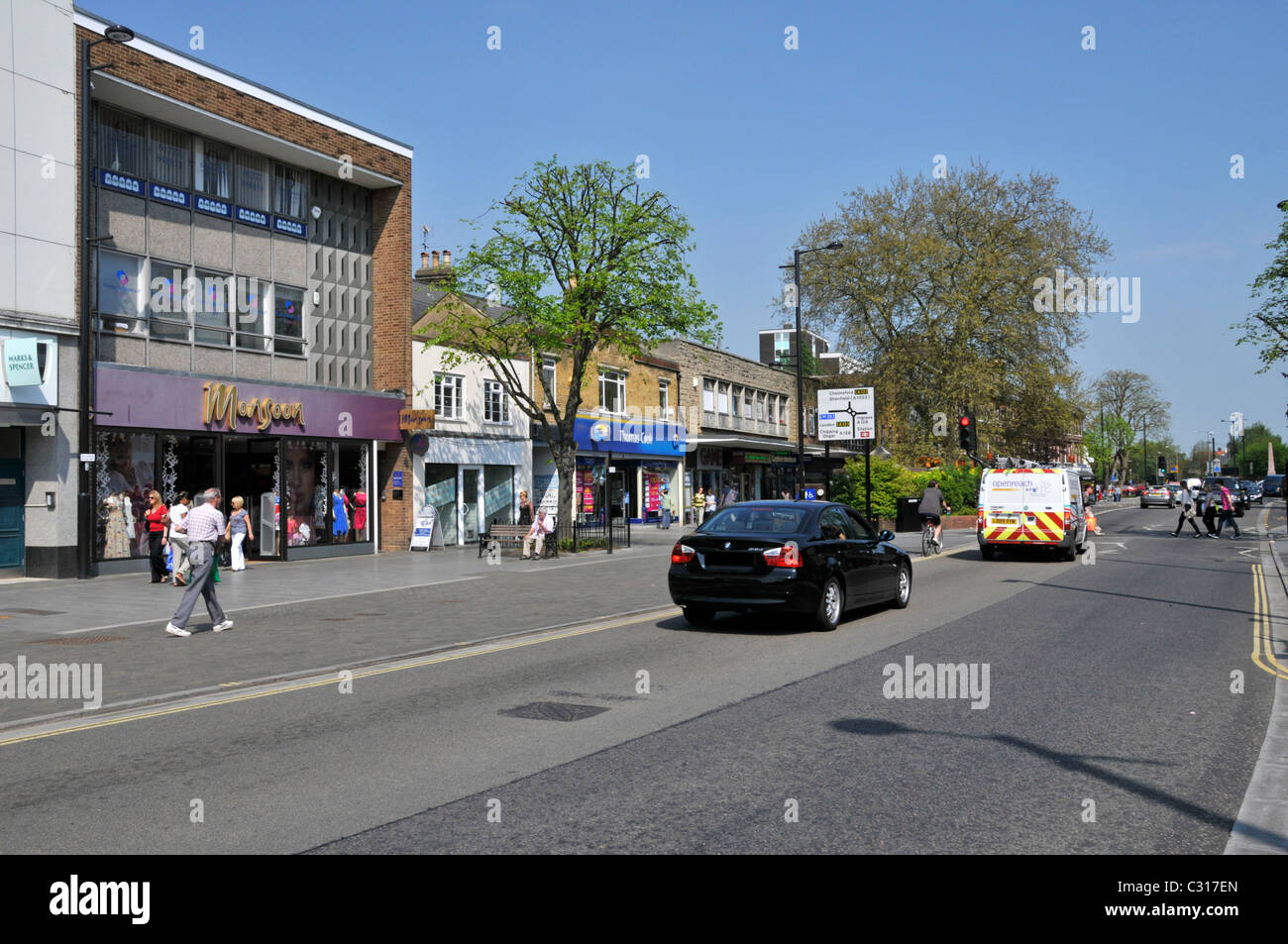 Sunny blue sky spring day in Brentwood Essex town centre shopping High Street with light traffic on the towns main road England UK Stock Photo