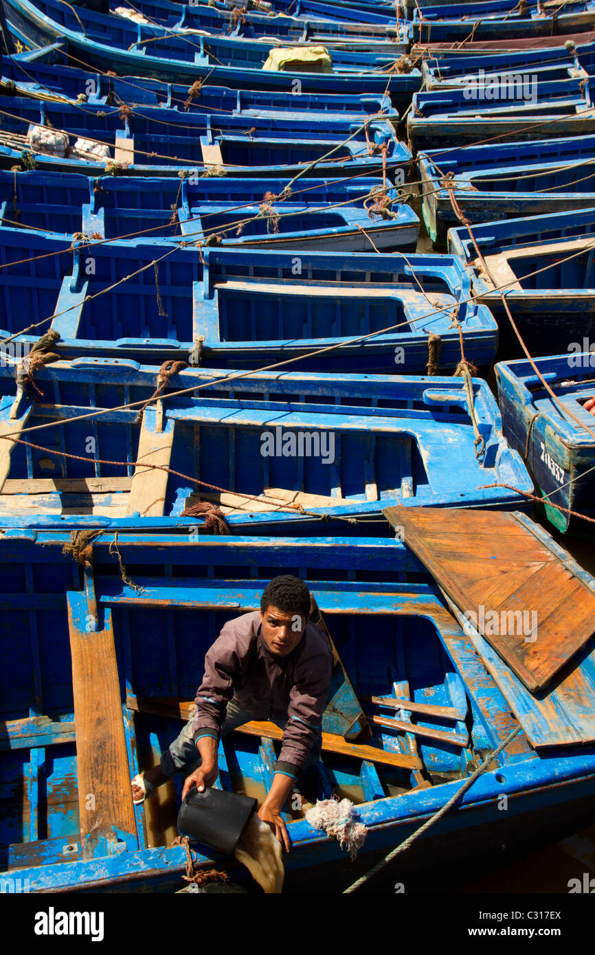 young man paddling out the water of a fishing boat in the Port of Essaouira Stock Photo