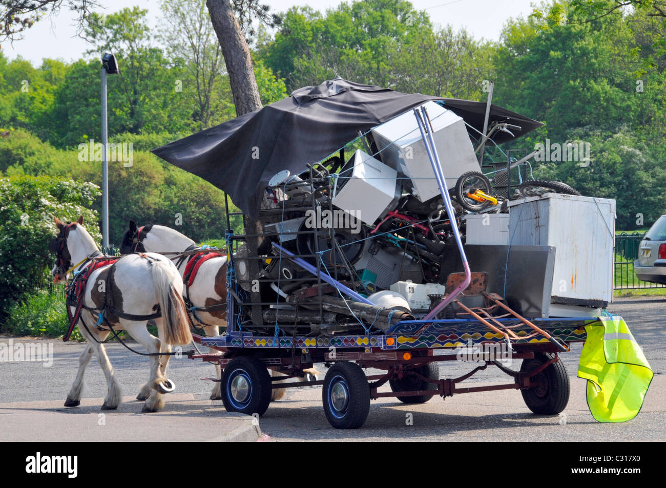 Rag and Bone man with horse & cart back view of load of junk white household goods recycling scene n village street high viz jacket Essex England UK Stock Photo