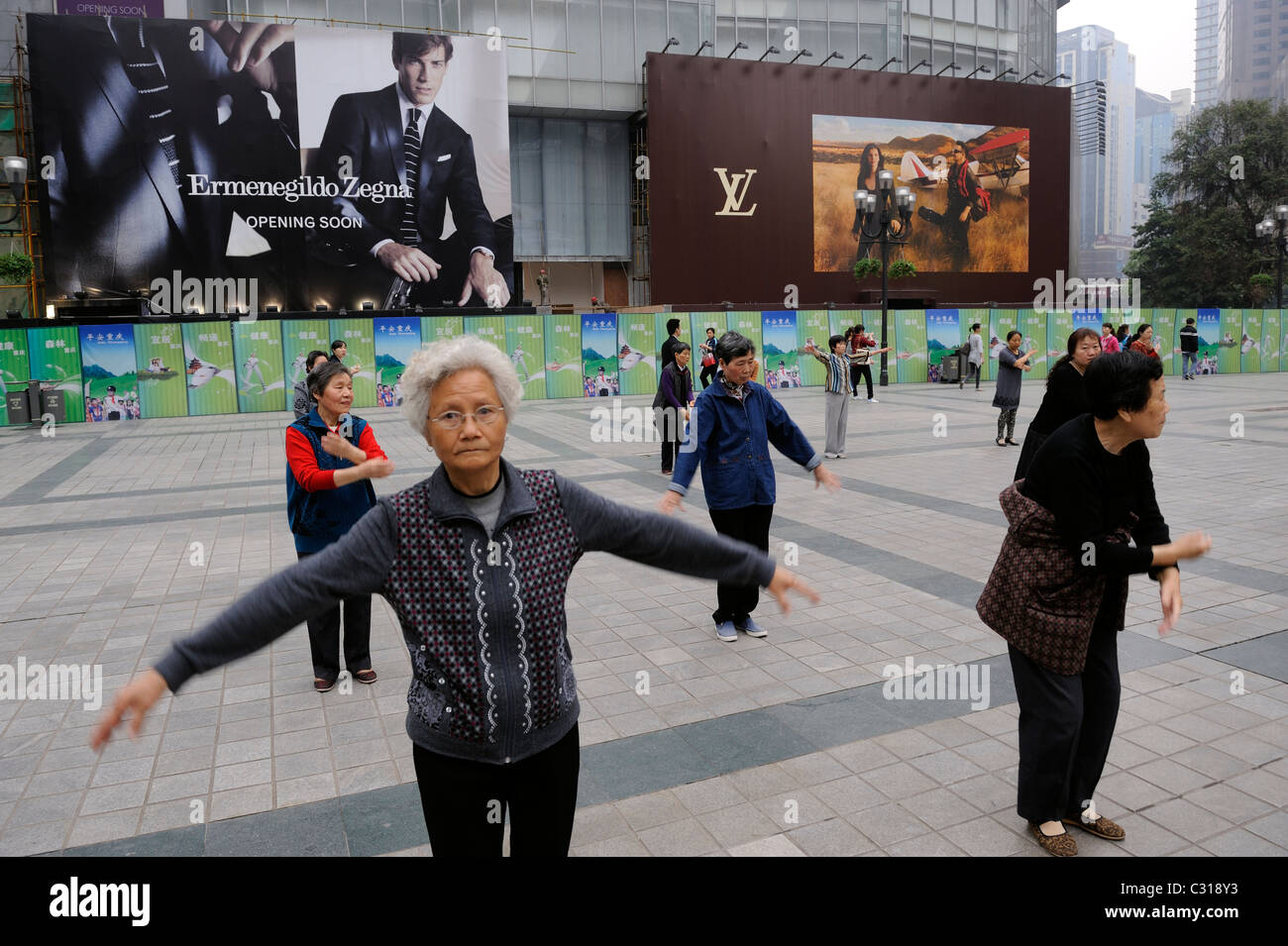 People morning exercise in front of Louis Vuitton and Ermenegildo Zegana billboards in downtown Chongqing, China. 22-Apr-2011 Stock Photo