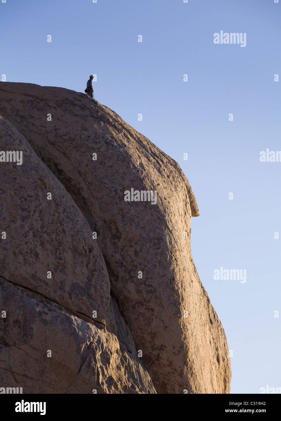 Rock climber standing on top of large boulder Stock Photo