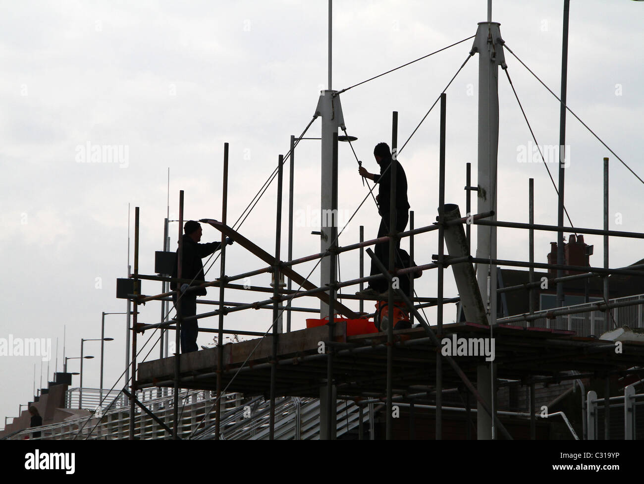 Builders in silhouette working on building. Stock Photo