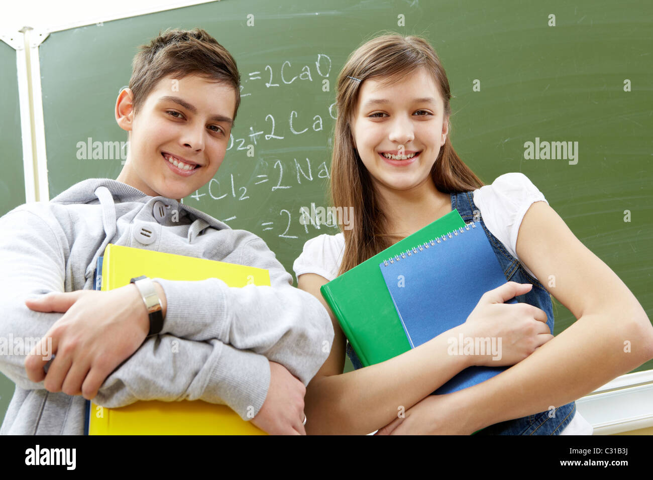 Portrait of happy guy and girl with books looking at camera Stock Photo ...