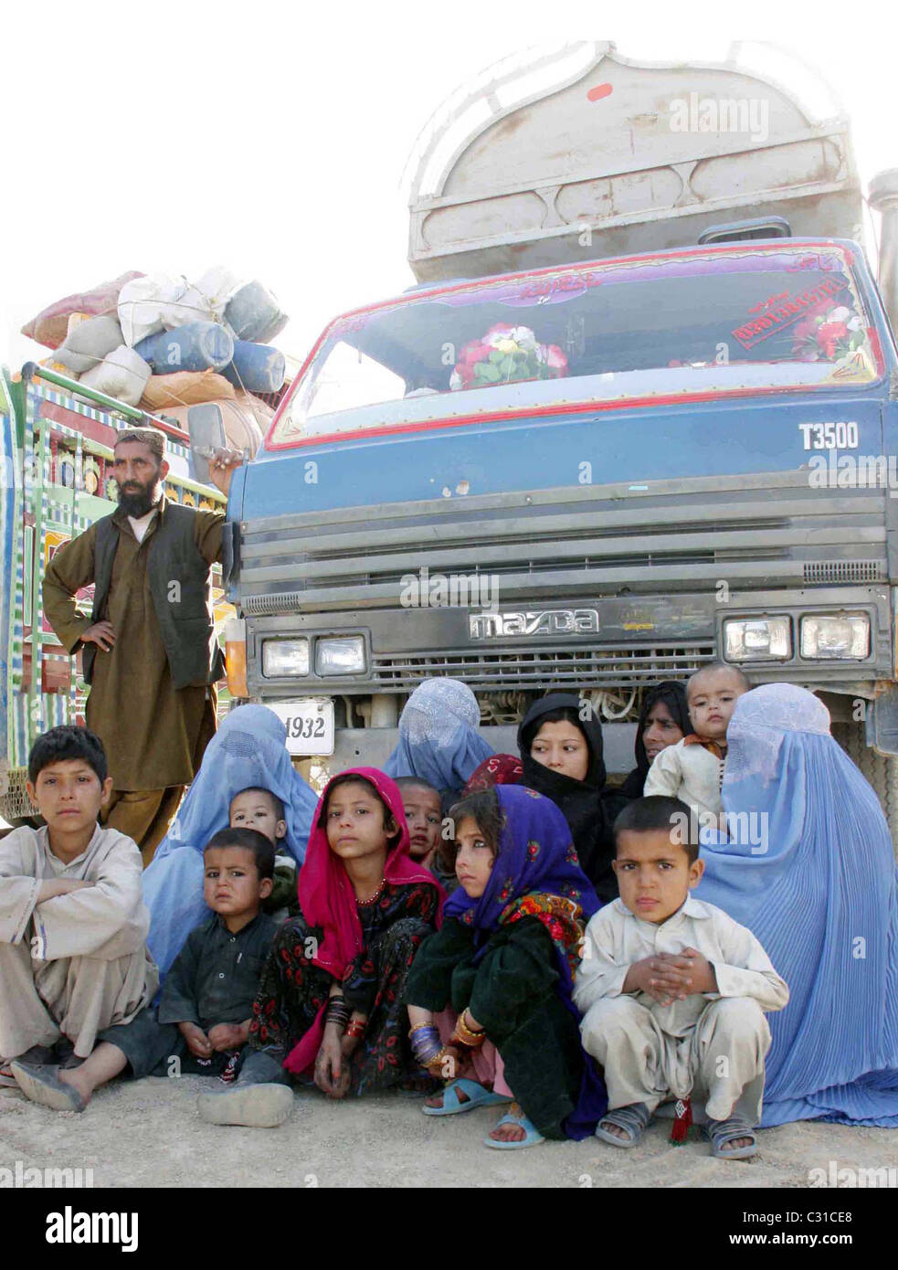 Afghan refugee women and children sit next to their vehicle as they are waiting for leave to their homeland at a United Nation Stock Photo