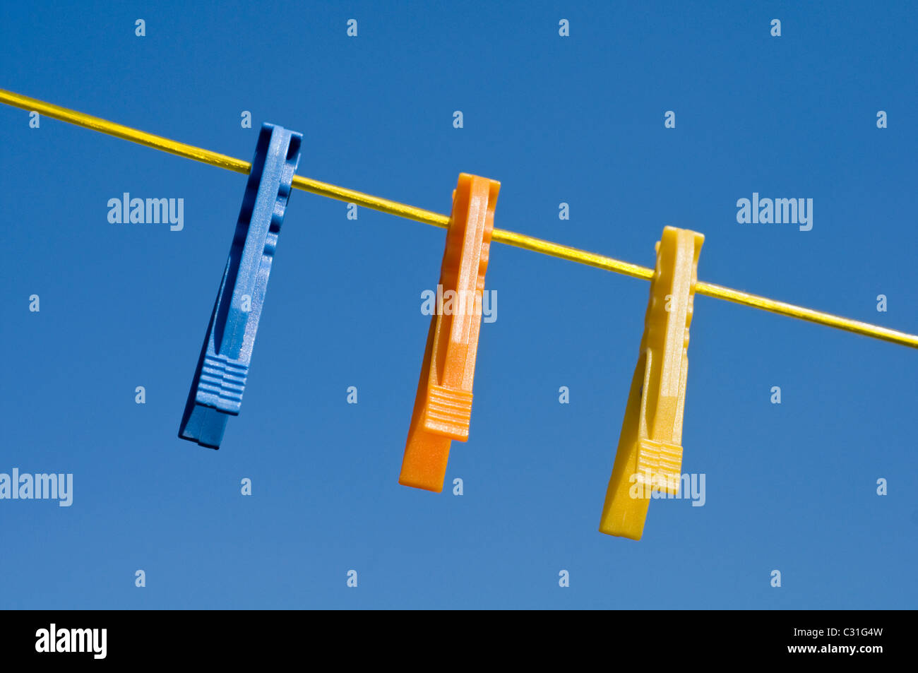 Colourful plastic clothes pegs hanging on a washing line Stock Photo