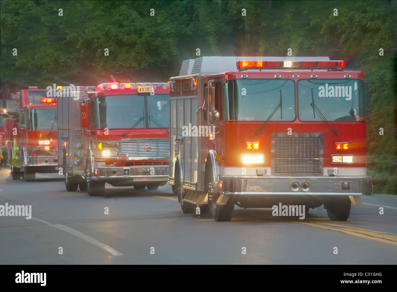 Three fire trucks on street with lights on Stock Photo