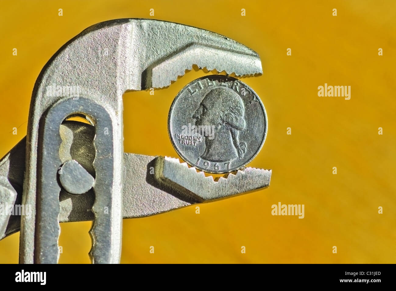 Close up of an Dollar Coin between pliers, concept of financial crisis Stock Photo