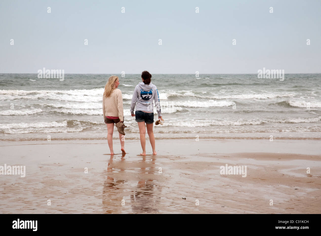 Two teenage girls paddling in the sea, Holkham beach, north Norfolk coast, UK Stock Photo