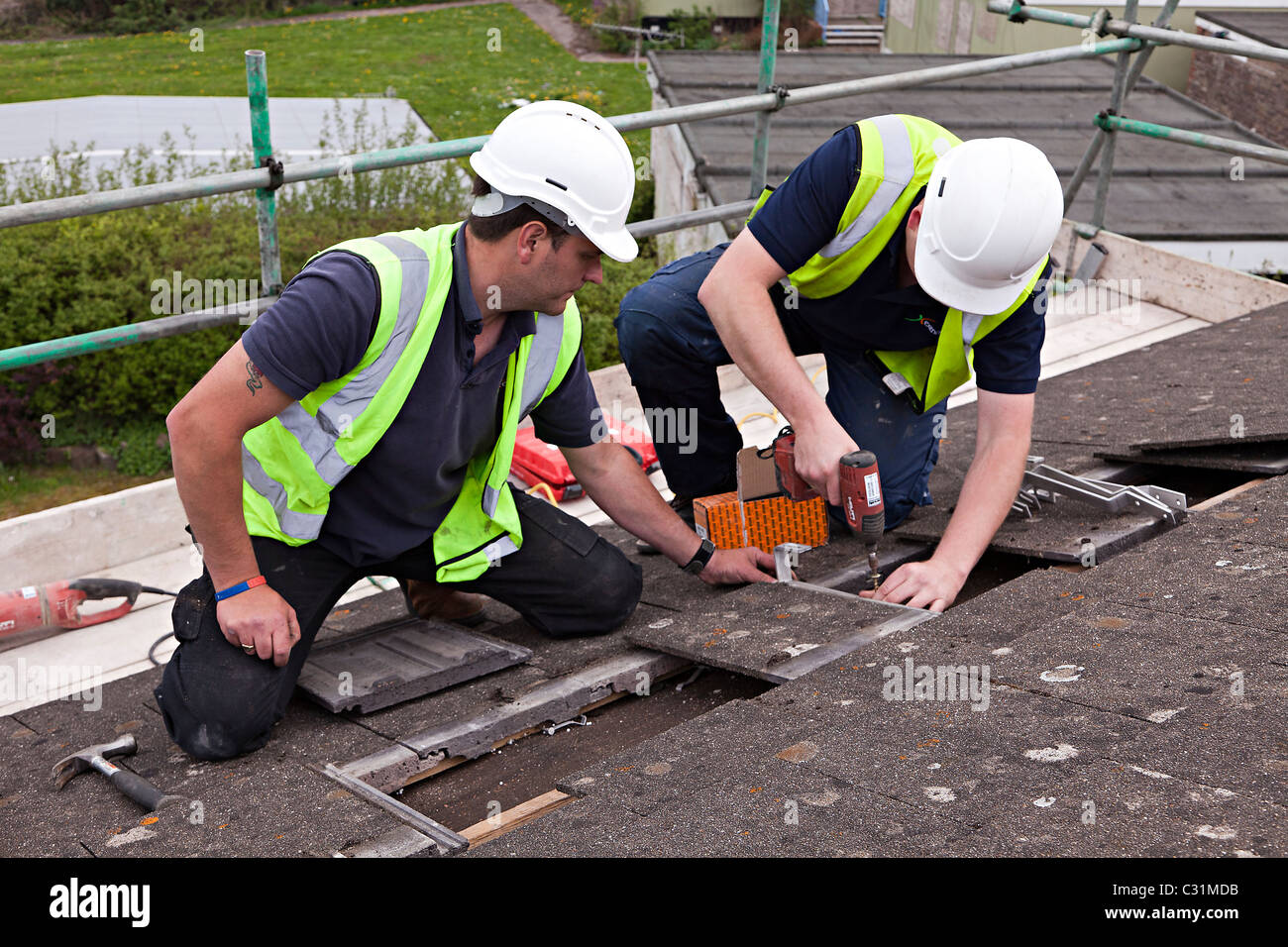 Men working on house roof in village fixing brackets for solar pv