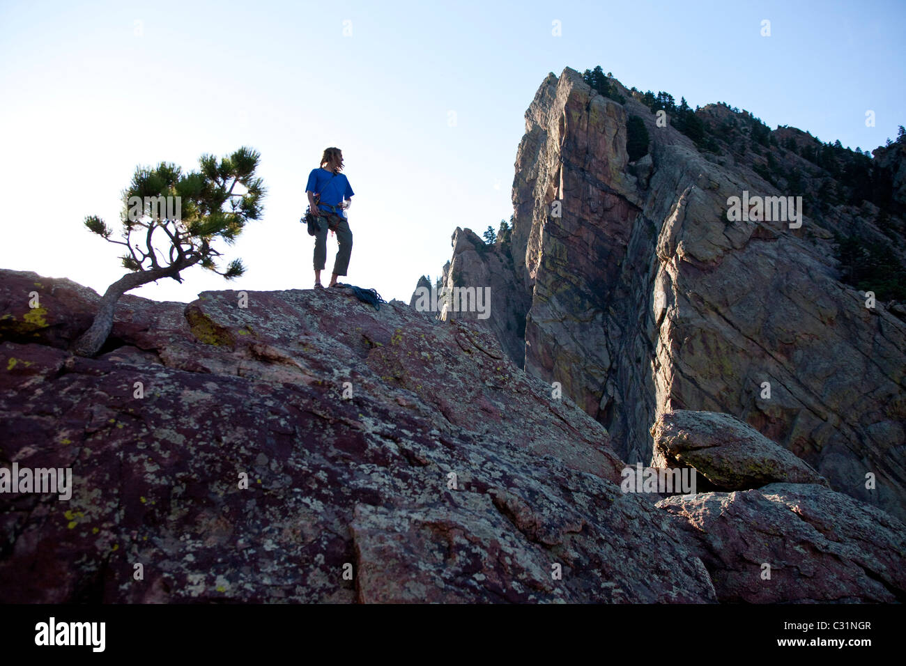 A young adult stands triumphantly on top of a 500 ft multi pitch trad