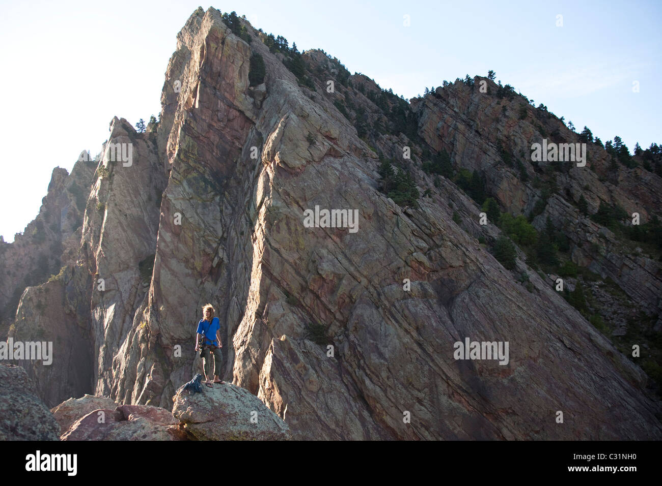 A young adult stands triumphantly on top of a 500 ft multi pitch trad