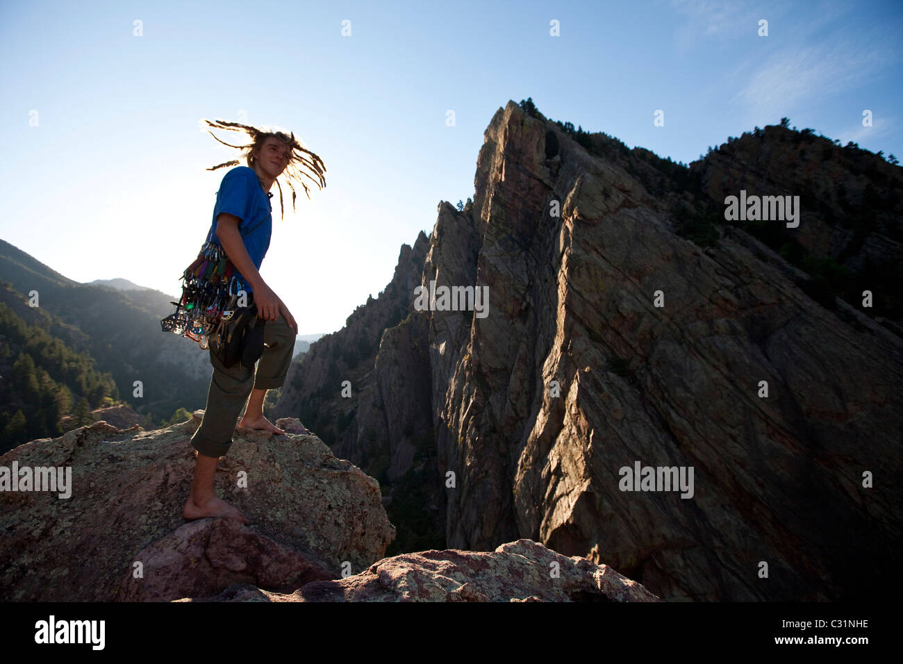 A young adult stands triumphantly on top of a 500 ft multi pitch trad