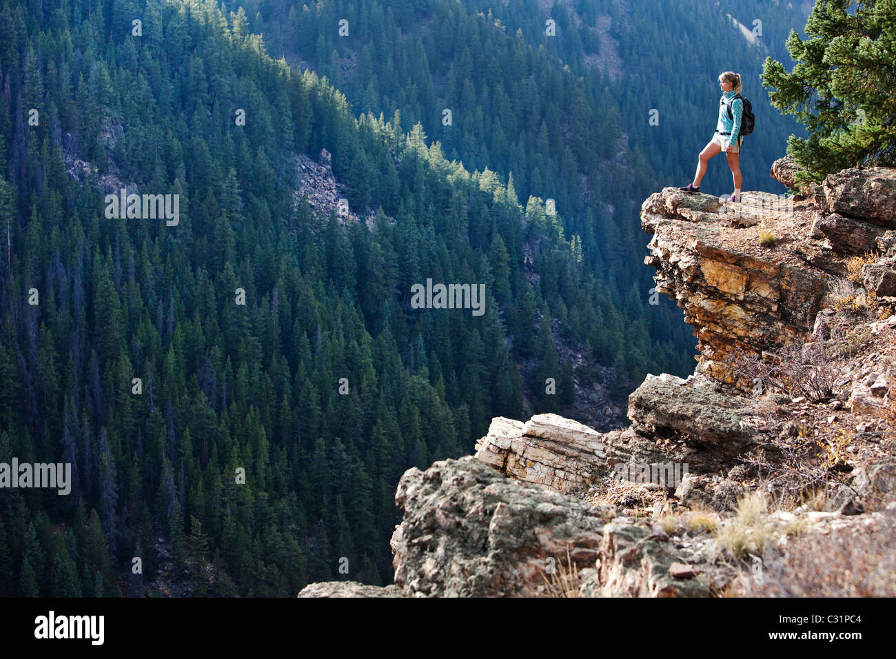 A young woman hiking takes a look over the edge of the canyon. Stock Photo