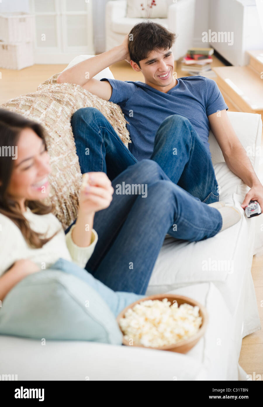 Couple eating popcorn and watching television Stock Photo