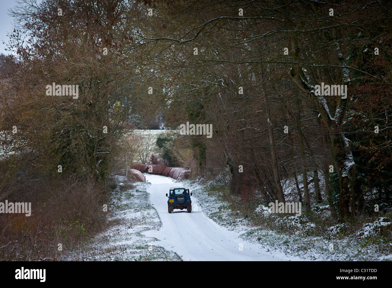 Land Rover in country lane in frosty wintry landscape in The Cotswolds, Oxfordshire, UK Stock Photo