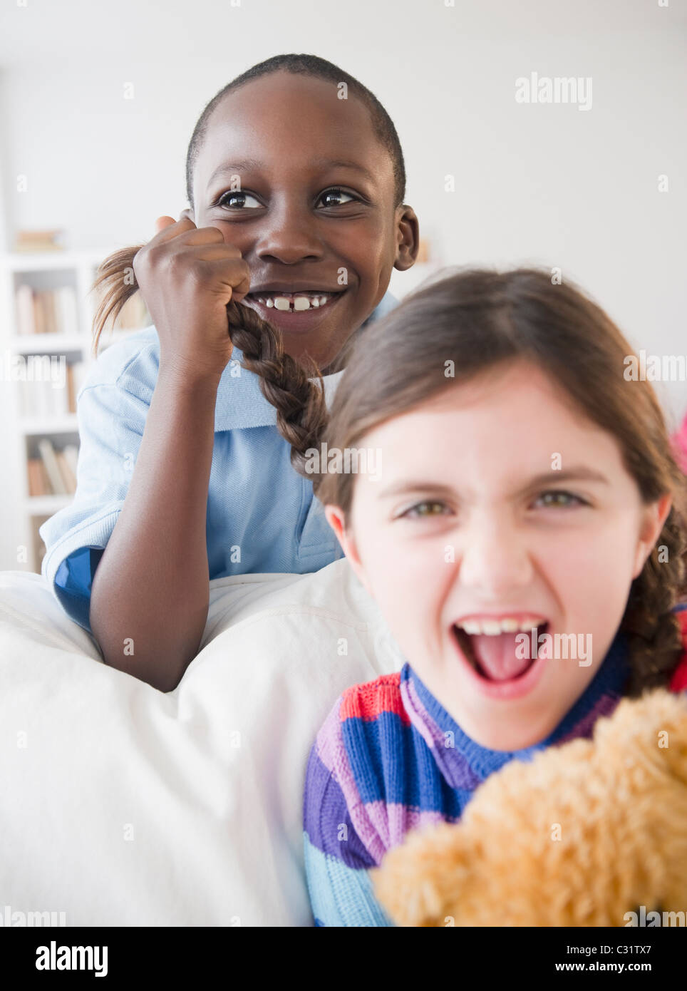 Grinning boy pulling girls braid Stock Photo Alamy