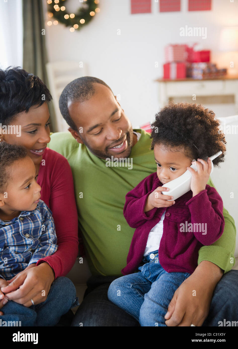 Black family watching girl talking on telephone Stock Photo - Alamy