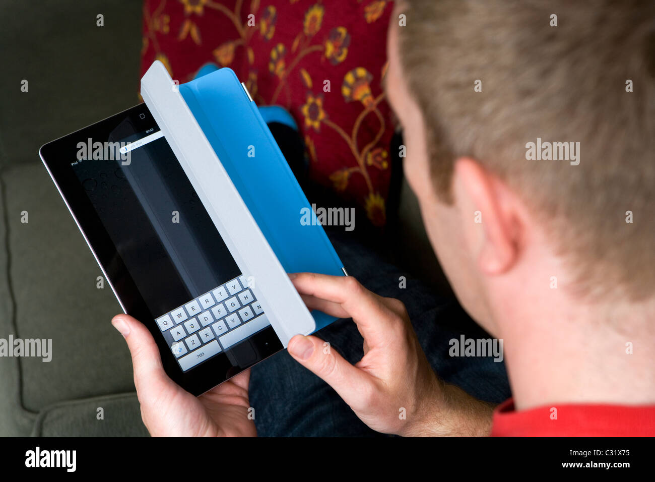 A man opening the smart cover on his Apple iPad 2 Stock Photo