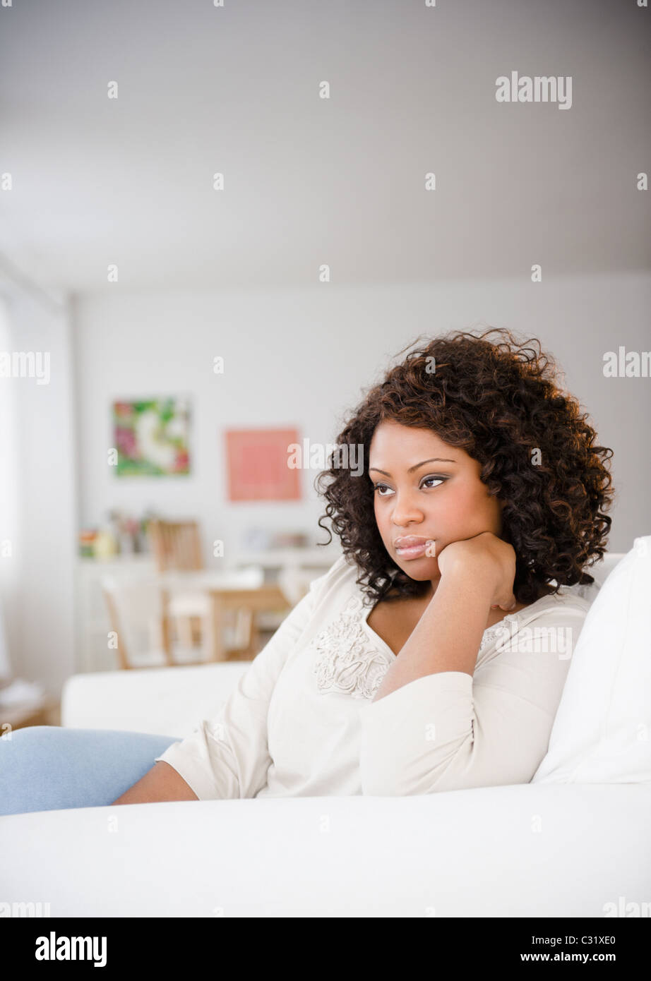 Sad African American woman sitting on sofa Stock Photo - Alamy