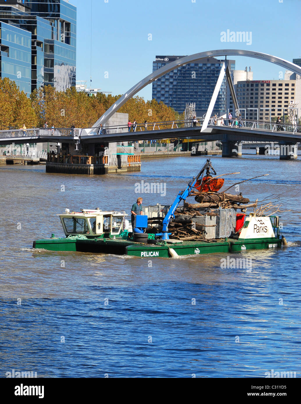 Melbourne Parks Dept collecting Yarra River rubbish by crane and barge, central Melbourne city, Victoria, Australia Stock Photo
