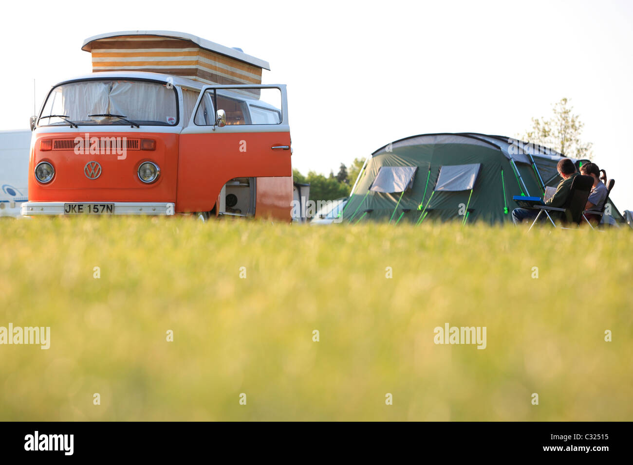 Couple sitting by tent and Volkswagen W camper van in a field in the morning light camping in East Sussex Stock Photo