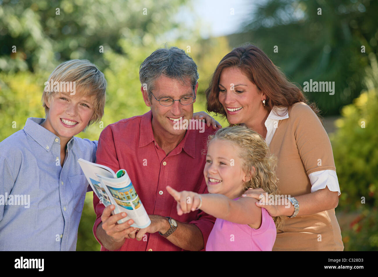 Family looking at guidebook and pointing Stock Photo