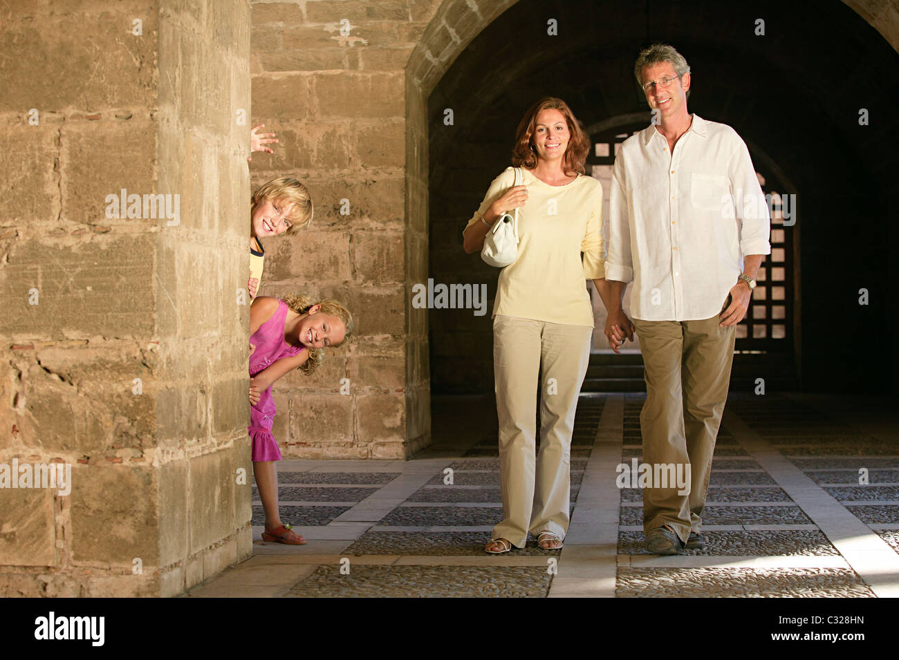 Parents walking and children behind pillar Stock Photo