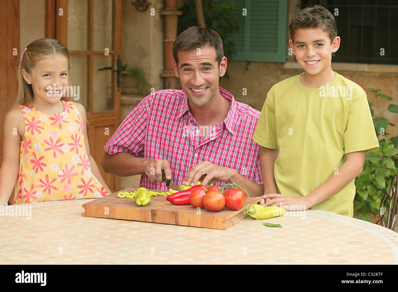 Children and father chopping vegetables outdoors Stock Photo